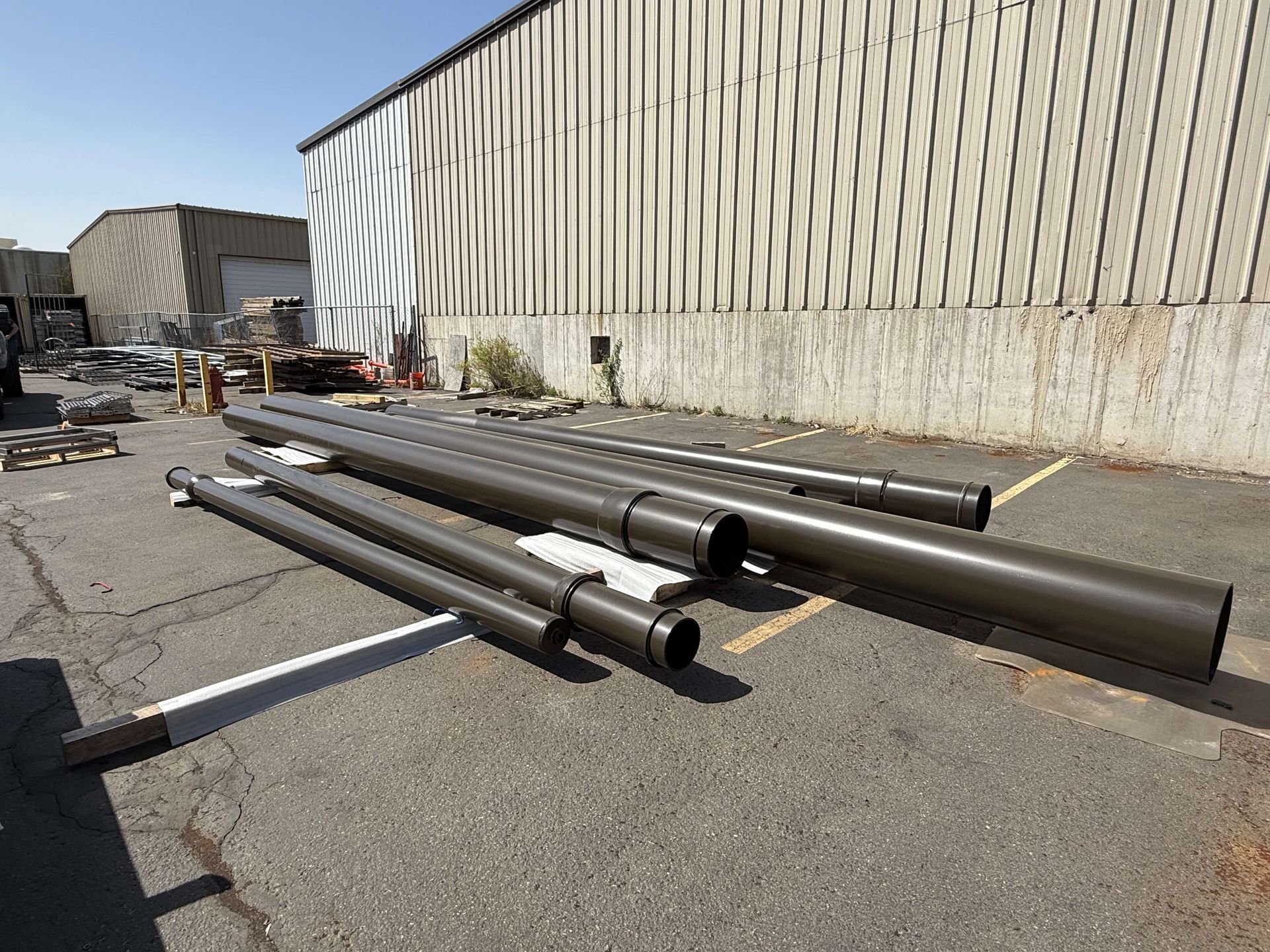 A bunch of pipes that just got powder coated are lying on the ground in front of a building