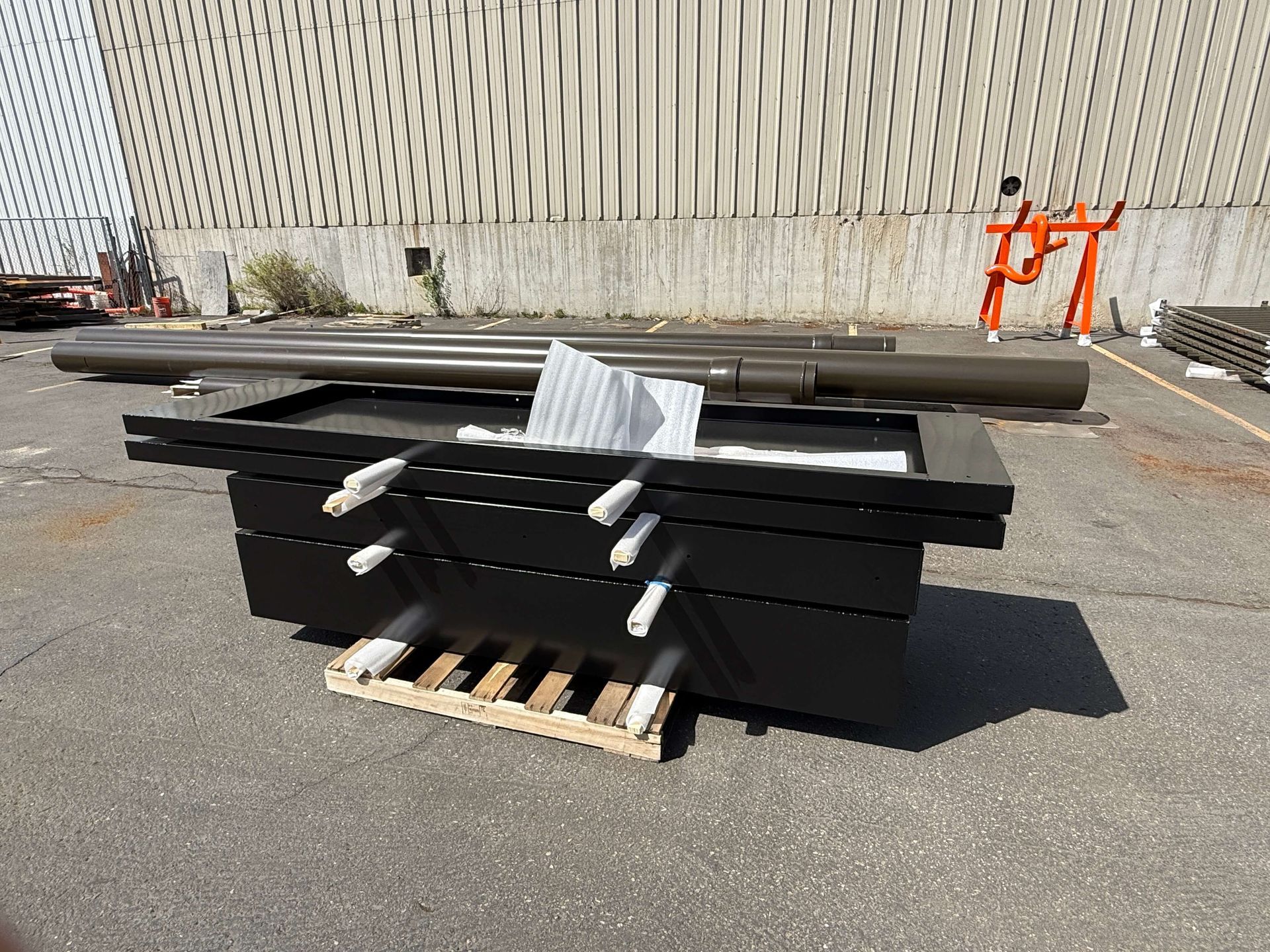 A stack of black powder coated boxes sitting on top of a wooden pallet.