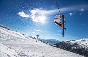 A skier is doing a trick in the air while skiing down a snow covered slope.
