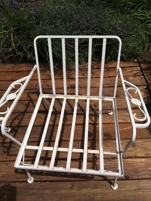 A white wrought iron chair is sitting on a wooden deck.