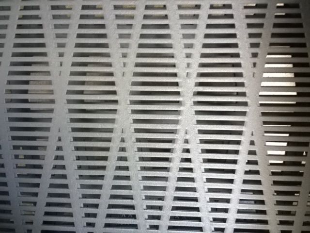 A close up of a metal wall with holes in it.