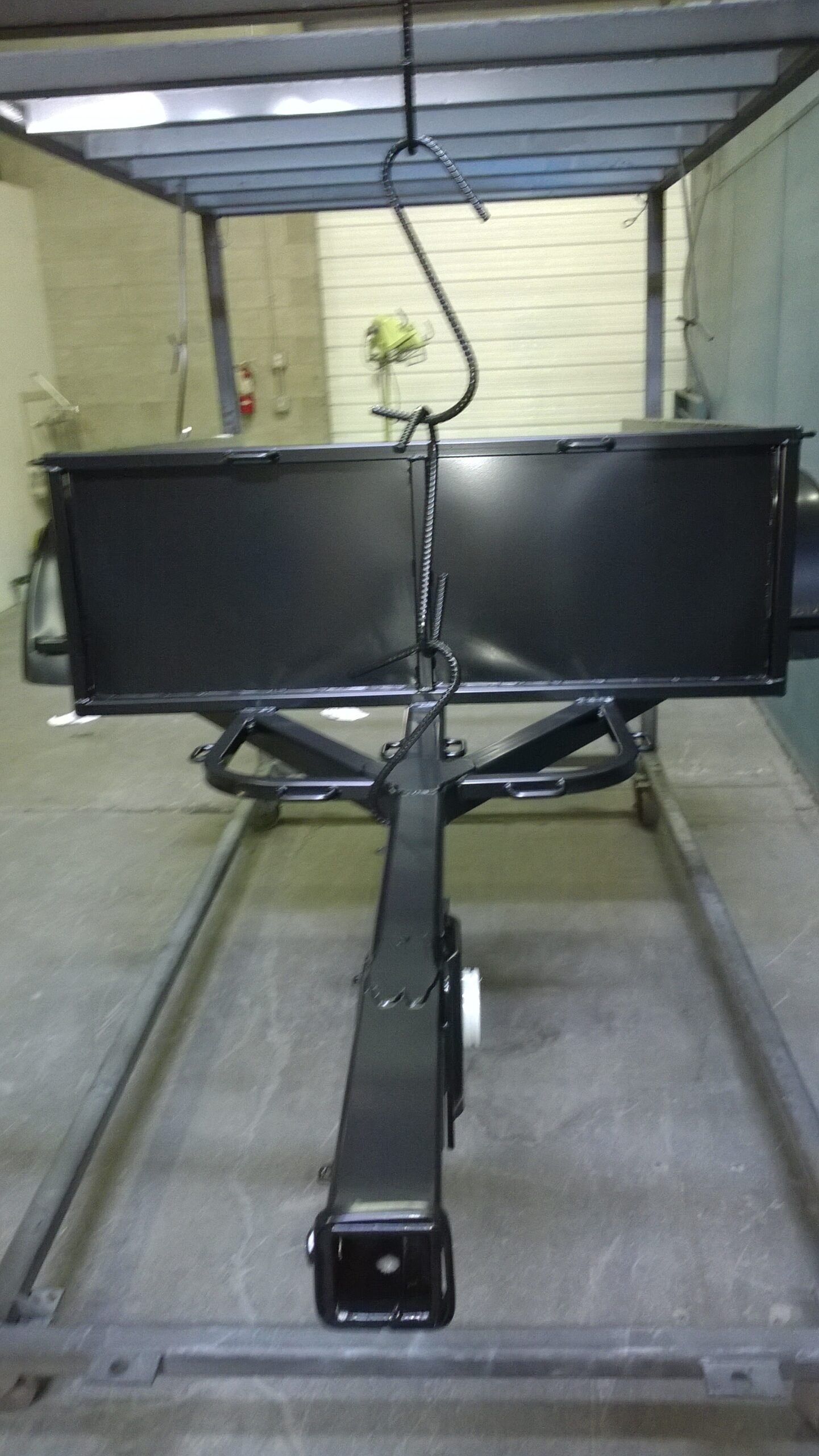 A black trailer is sitting on a concrete floor in a garage.