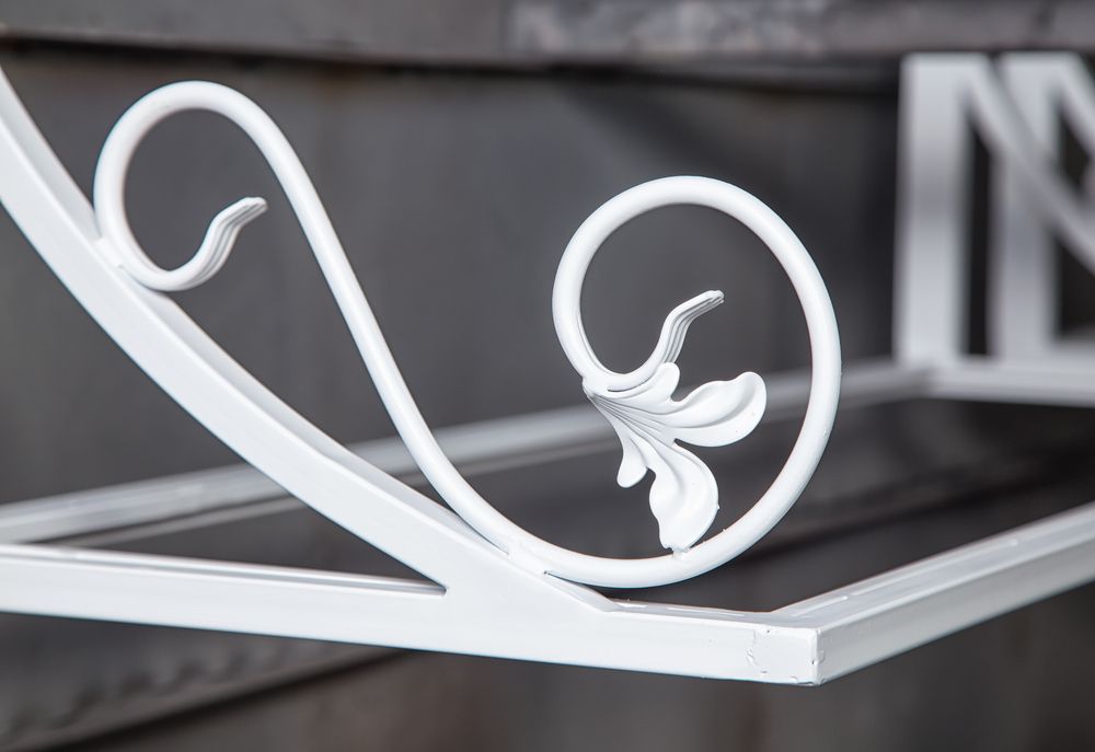 A white wrought iron shelf with a flower design on it