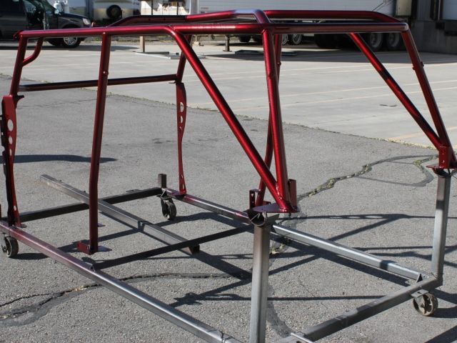 A red metal frame with wheels is sitting on the ground