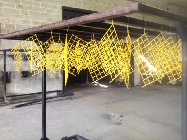 A bunch of yellow squares are hanging from a rack
