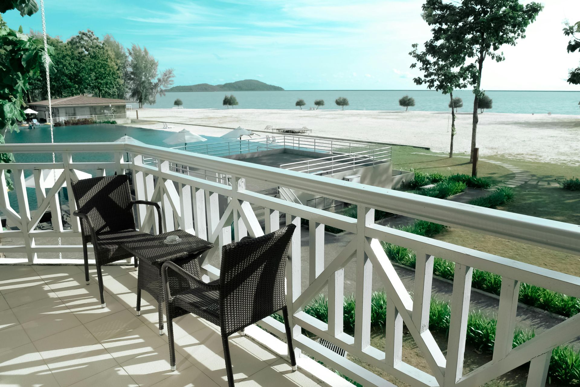 A balcony with chairs and a table overlooking the ocean