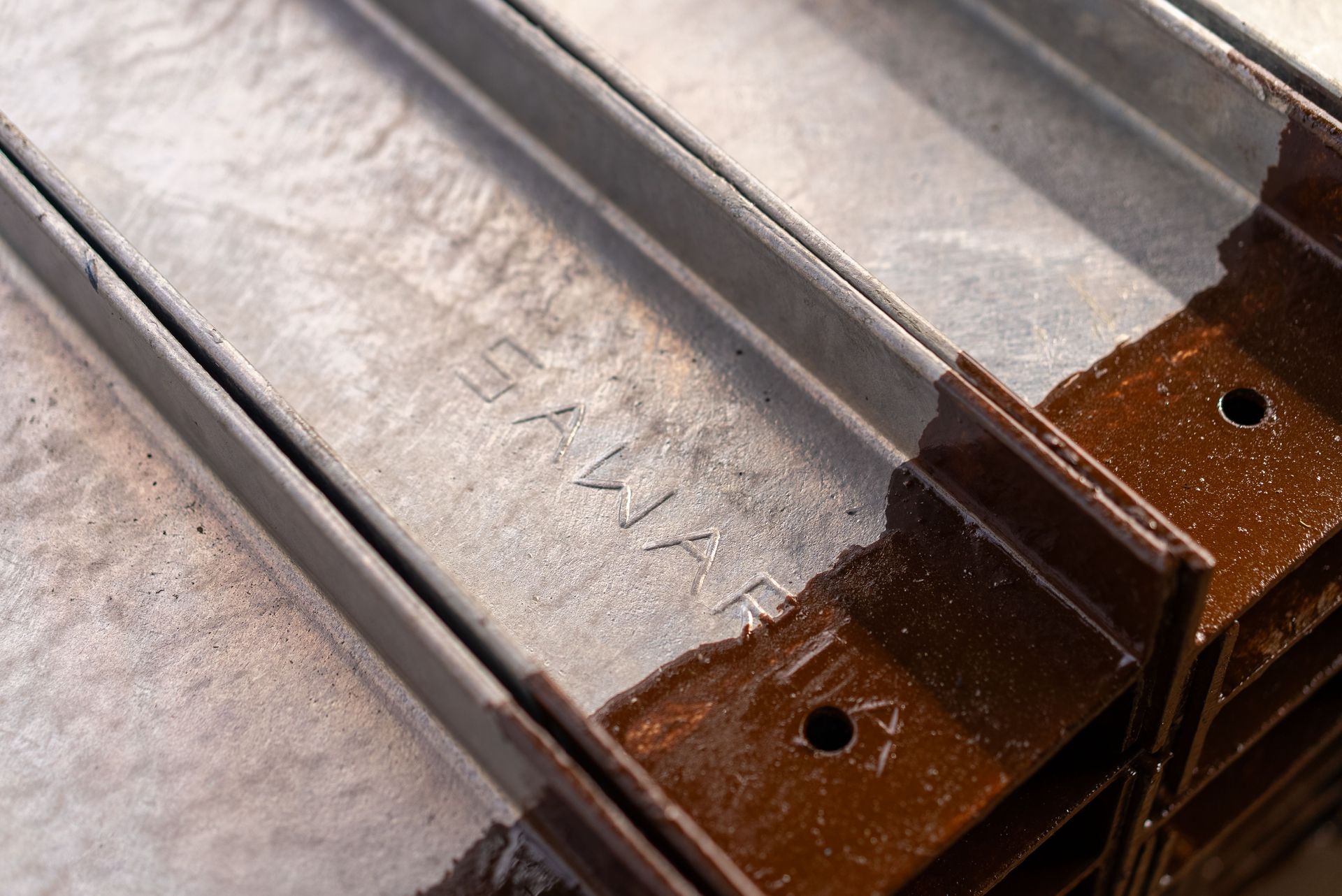 Close-up of clear plastic sleeves on a brown cardboard surface with a metal rail and mounting holes