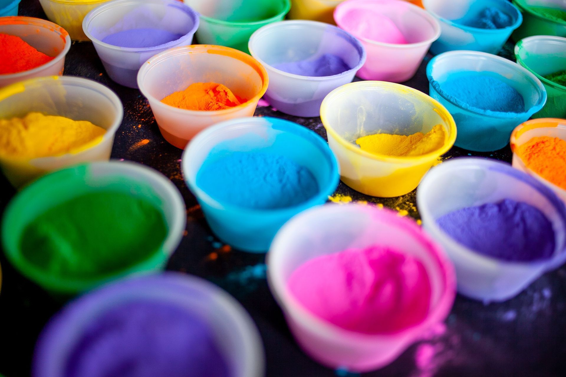 Rows of small cups filled with brightly colored powder in blue, pink, purple, yellow, and green