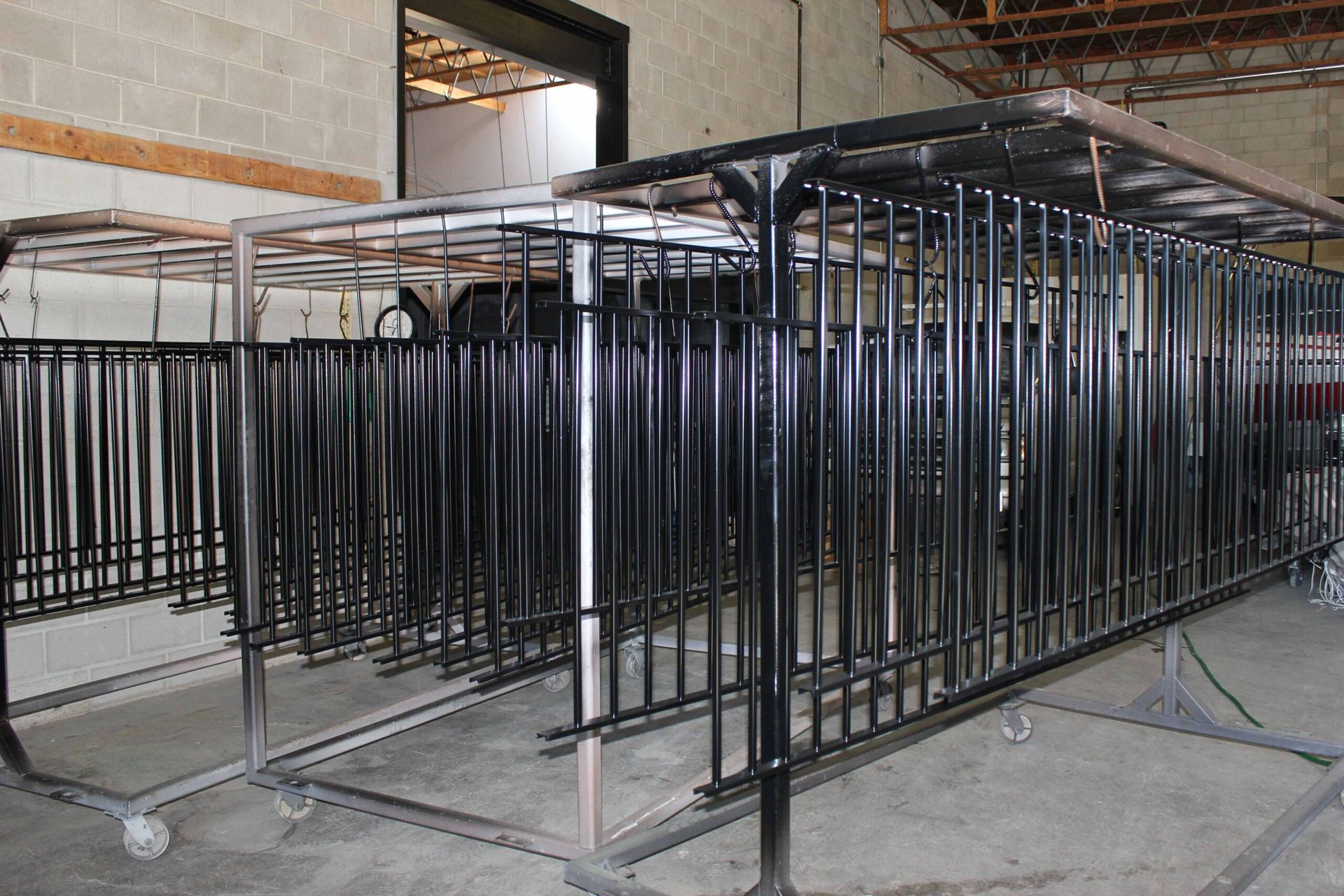 A row of black metal fences are sitting in a warehouse.
