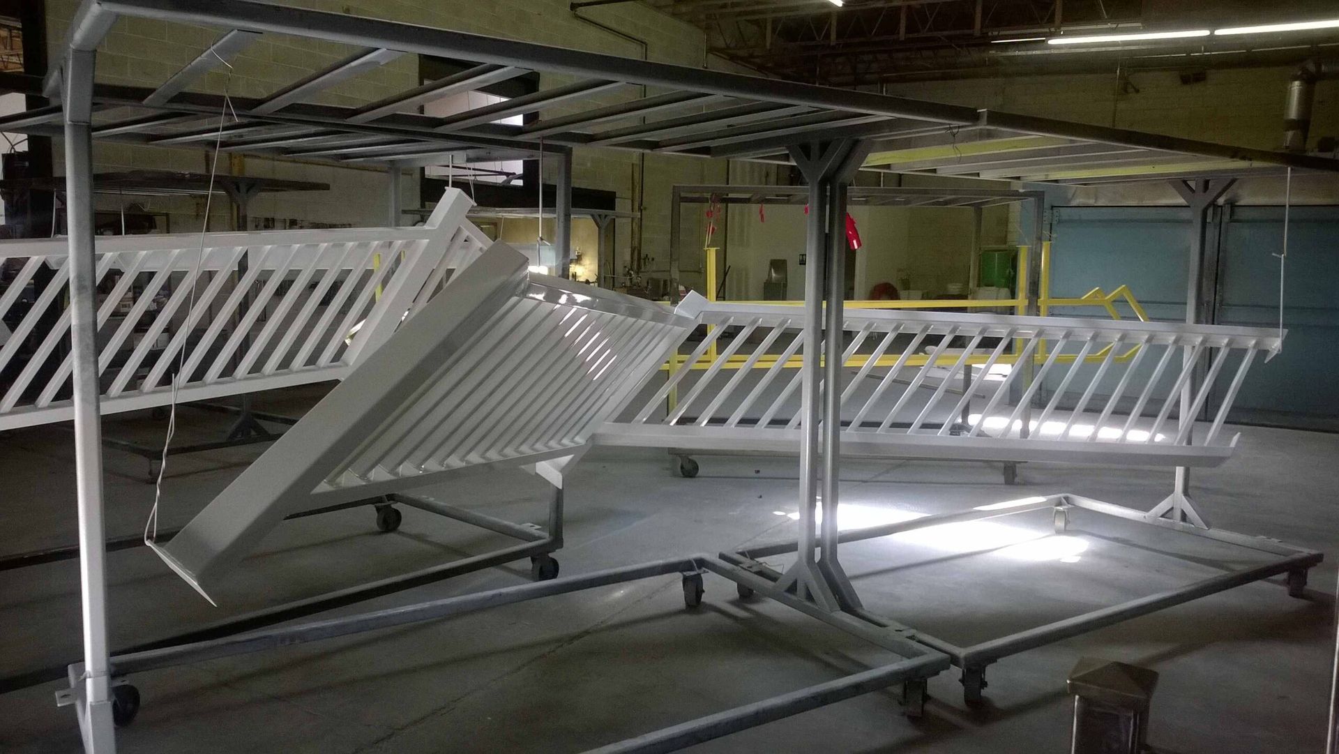 A white railing is being painted in a factory.