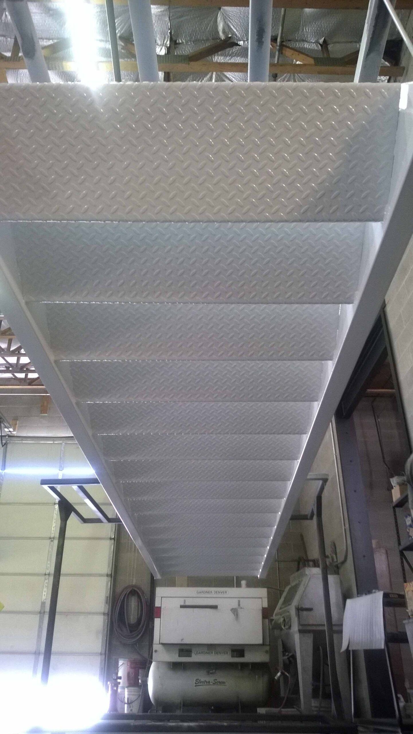 A metal staircase leading up to a ceiling in a garage.