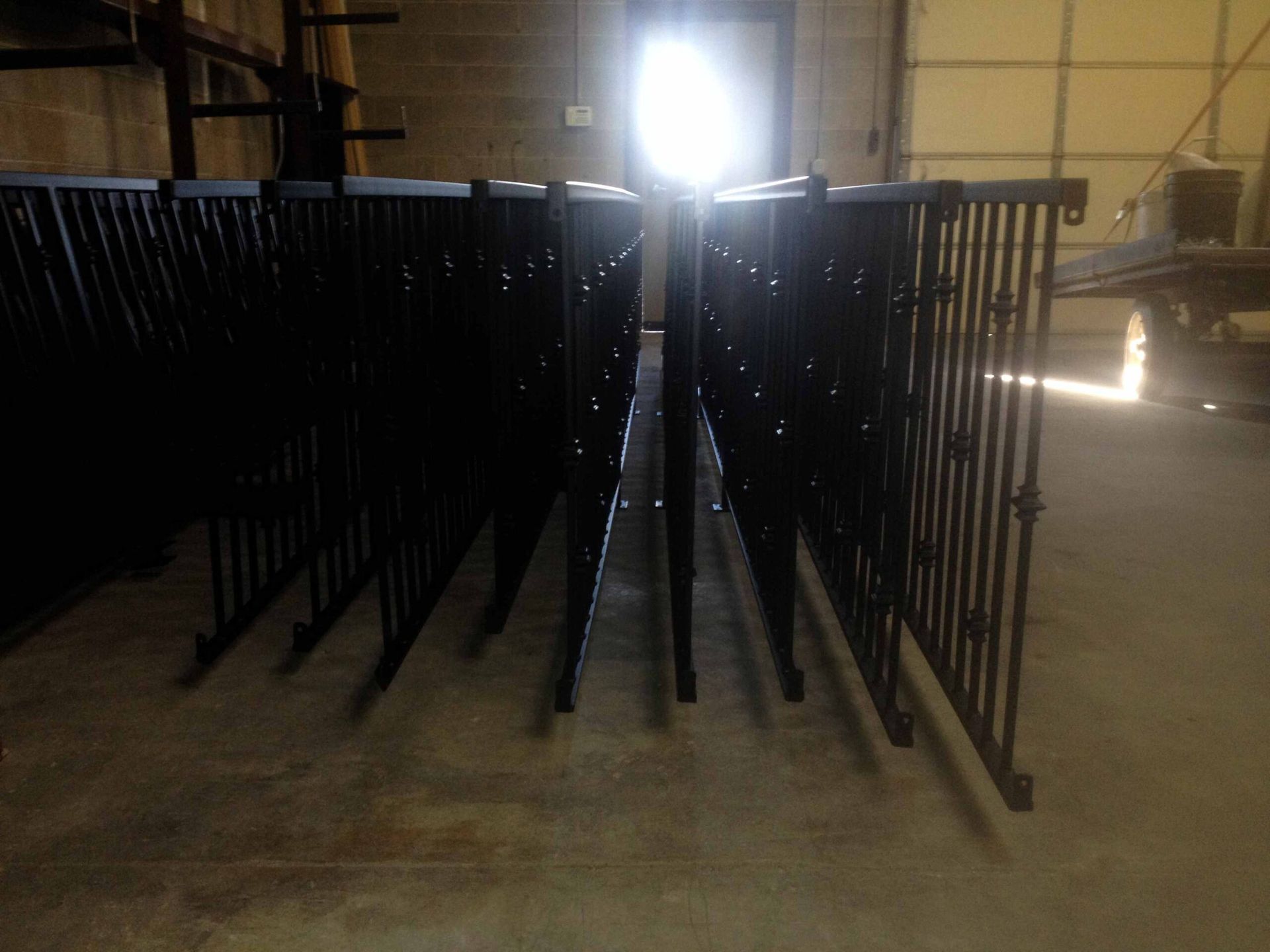 A row of black metal fences are lined up in a warehouse