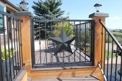 A wrought iron gate with a star on it is on a wooden deck.