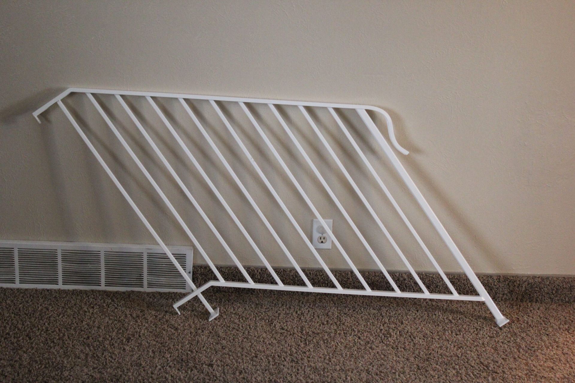 A white railing is laying on the floor next to a wall