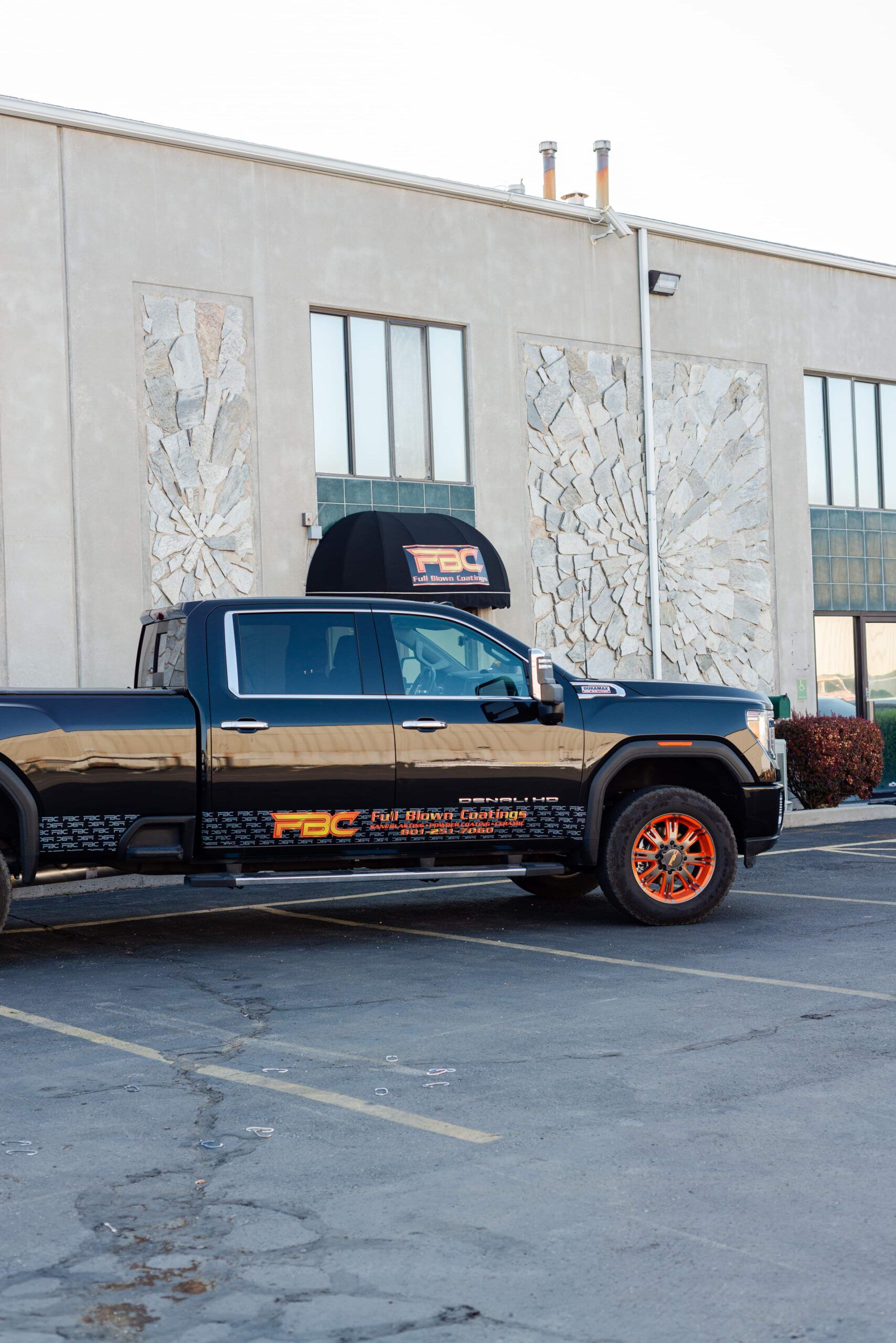 A truck is parked in front of a building in a parking lot.