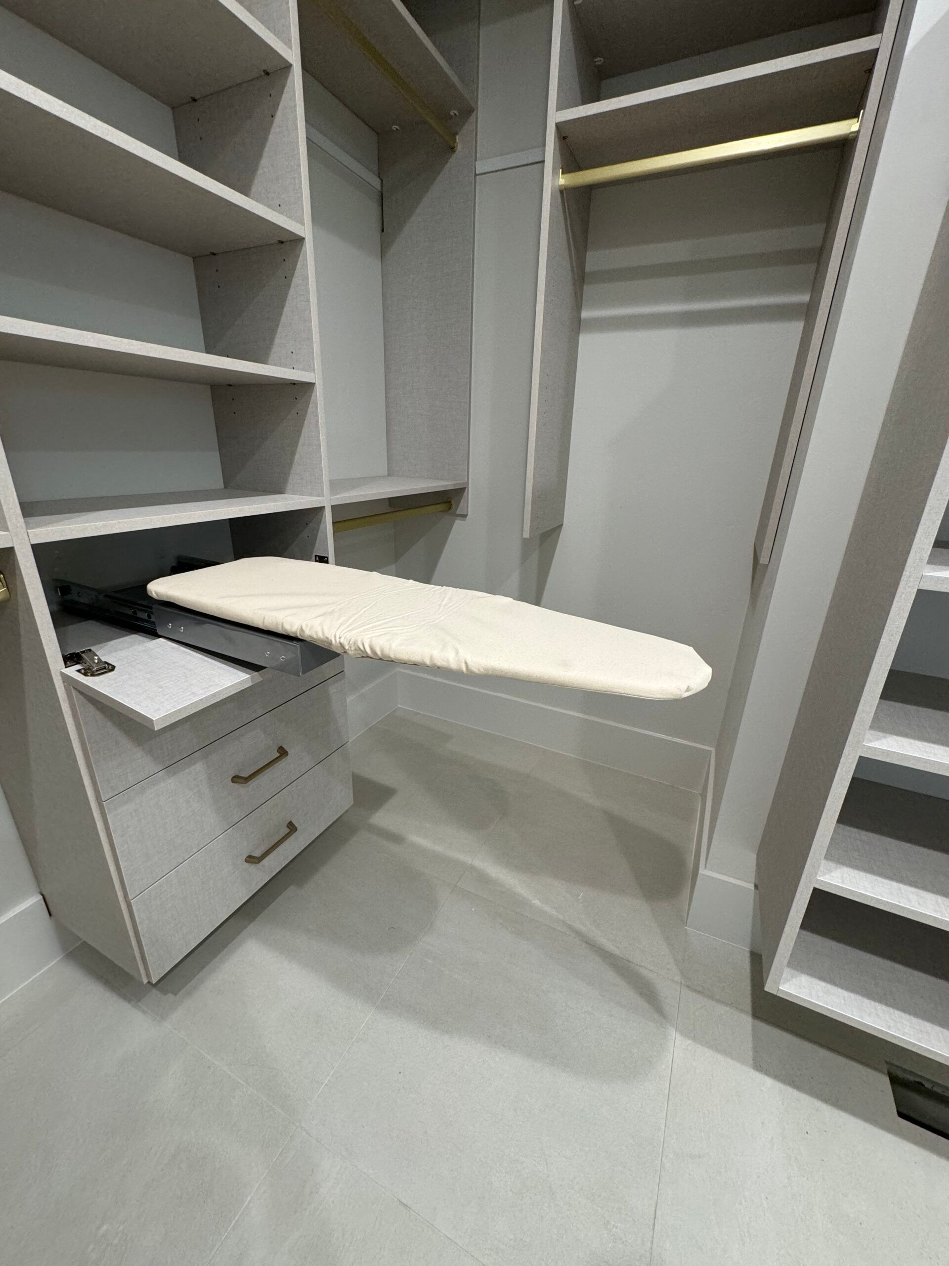 A walk in closet with a built in ironing board.