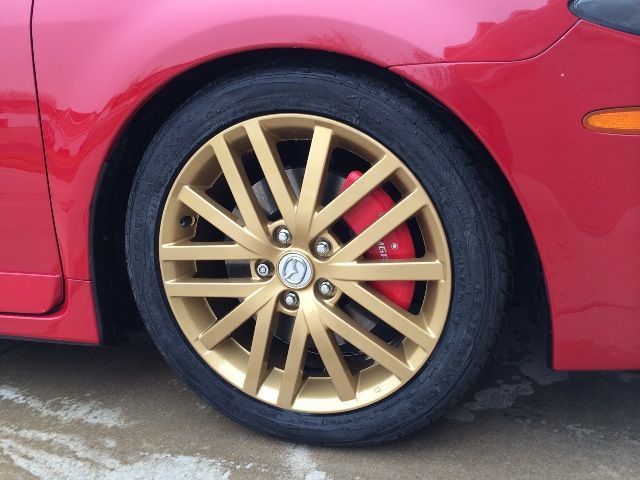A red car with gold rims and red brake calipers