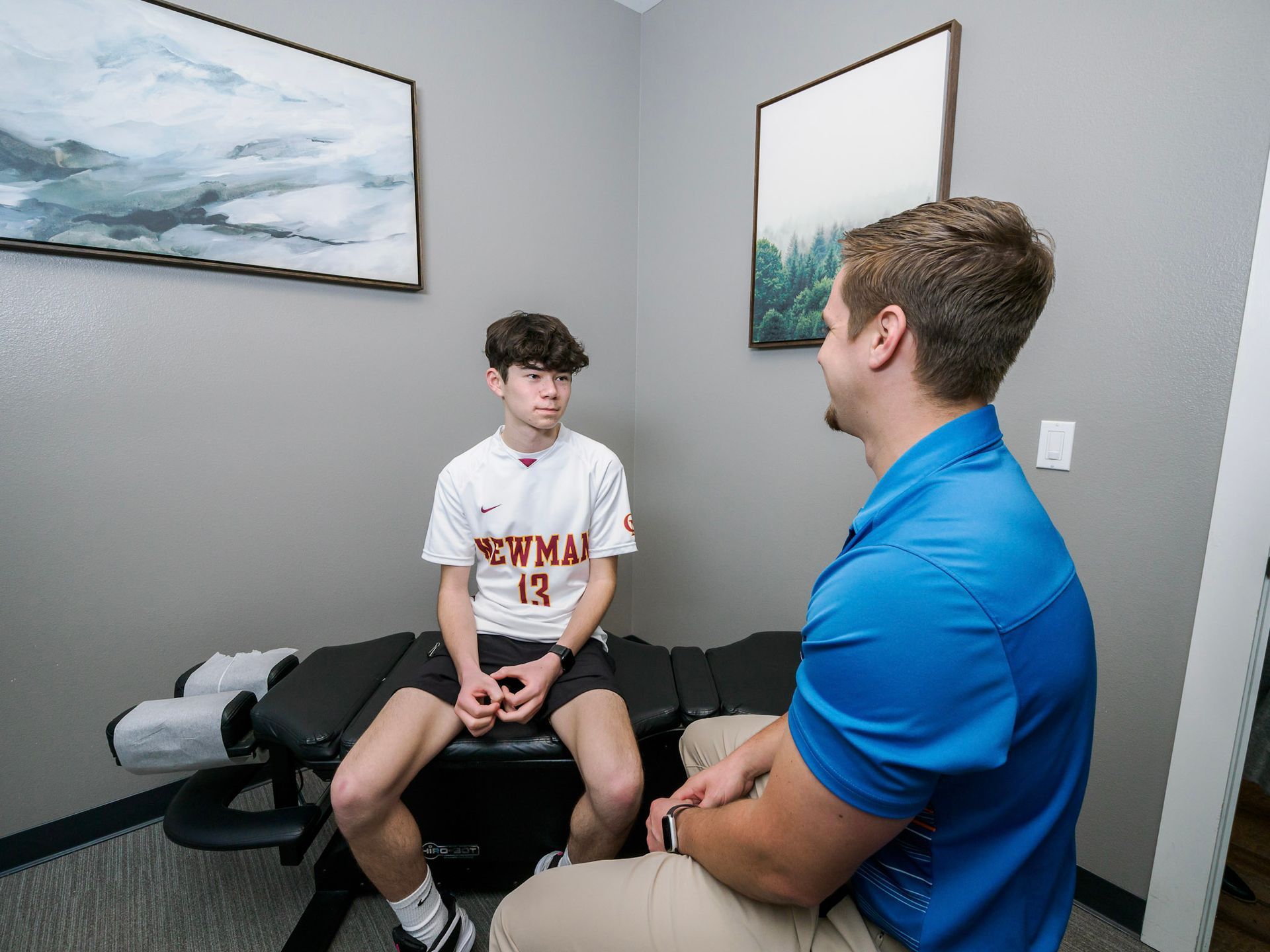A man is talking to a young boy who is sitting on a table.