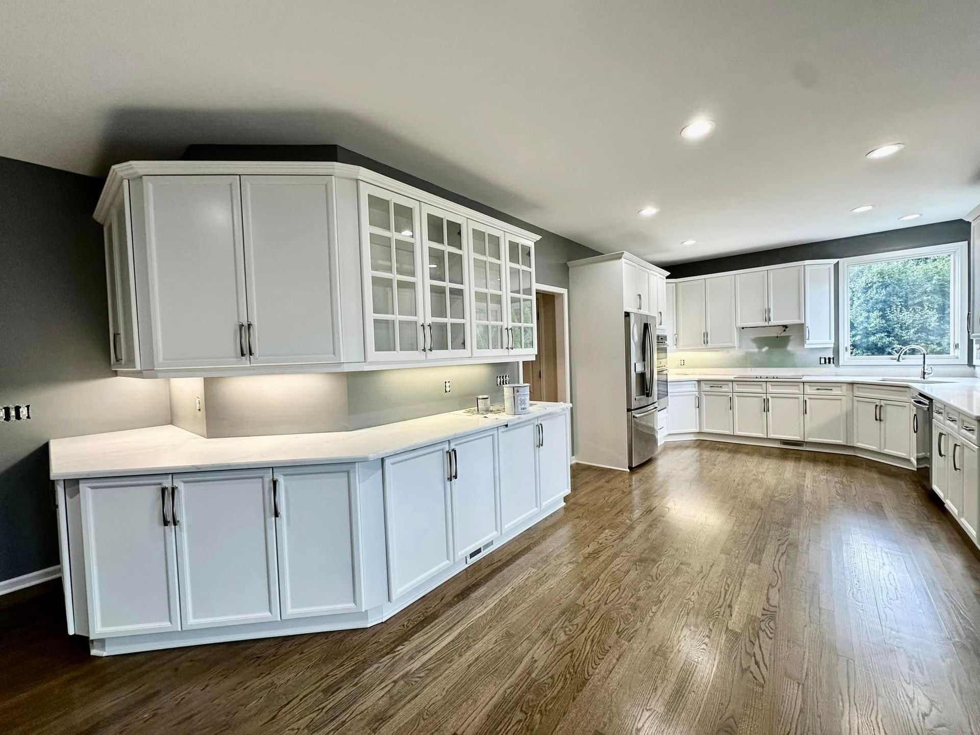 A large kitchen with white cabinets and hardwood floors.