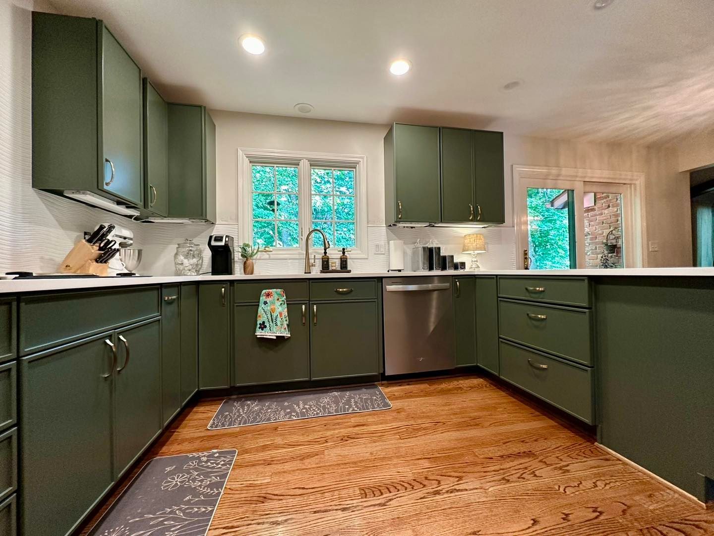 A kitchen with green cabinets and stainless steel appliances