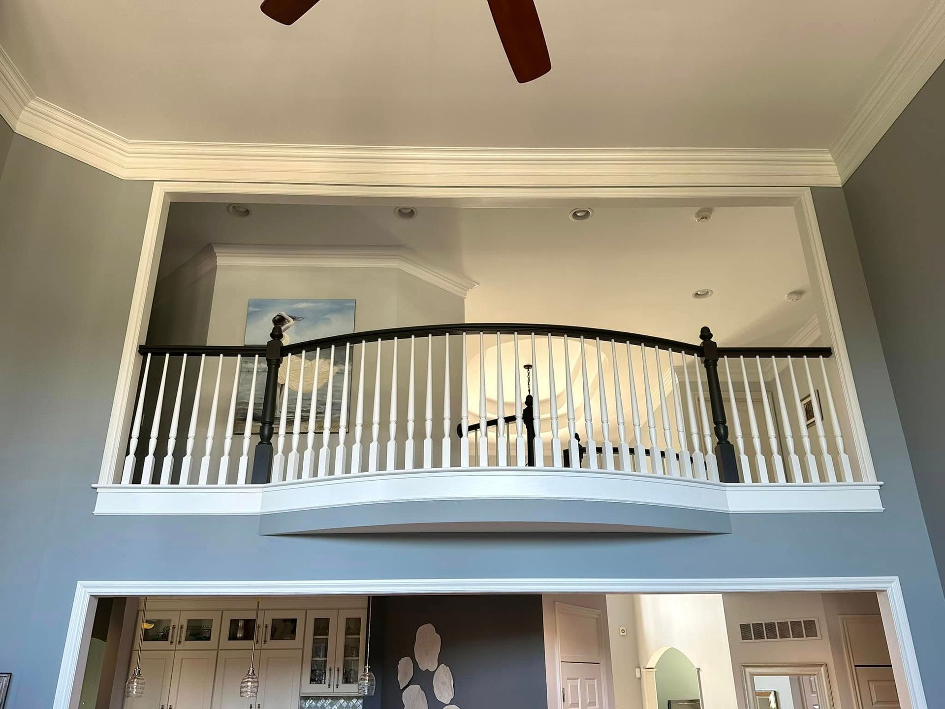 A living room with a balcony and a ceiling fan.