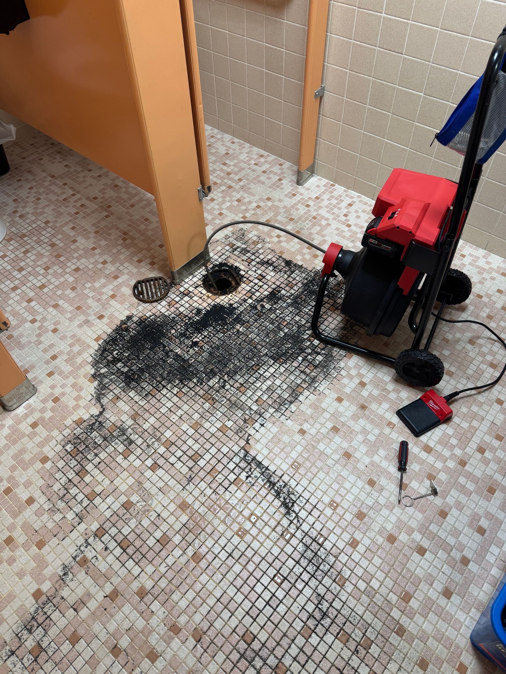 A vacuum cleaner is sitting on a tiled floor in a bathroom.