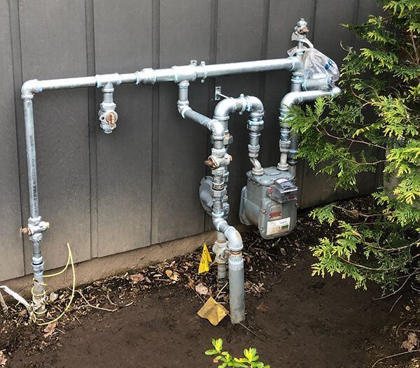 A gas meter is attached to a metal pipe outside