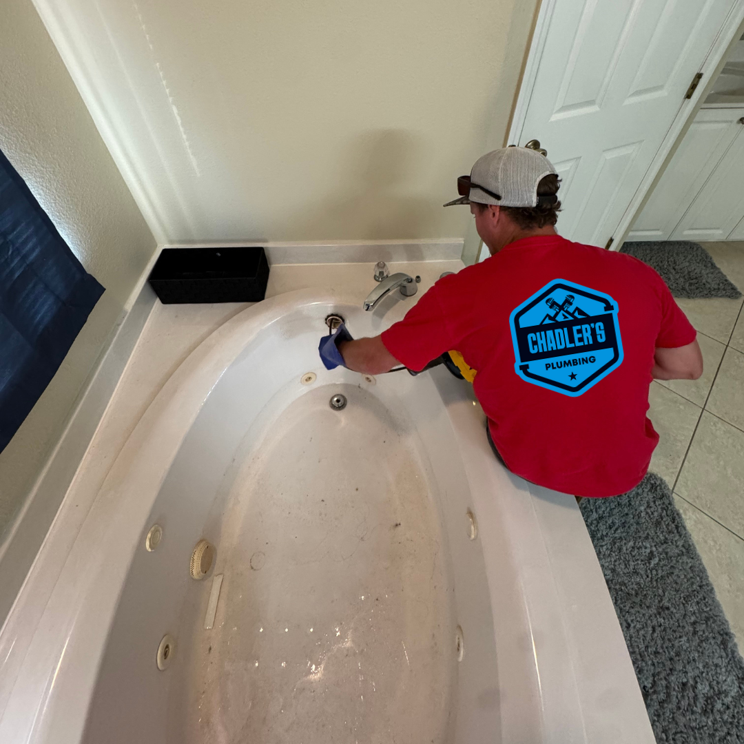 A man wearing a red shirt that says plumber 's on it sits in a bathtub