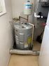 A water heater is sitting in a room next to a furnace.