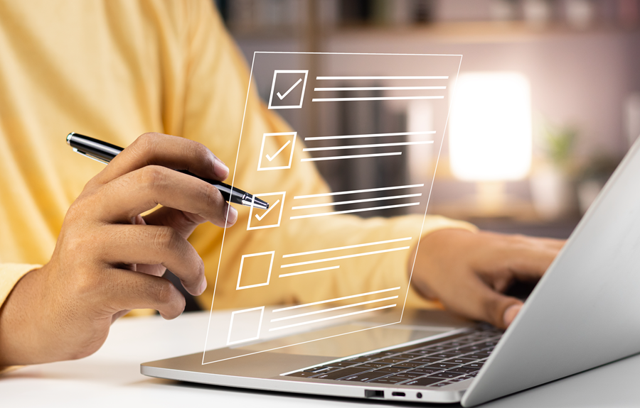 A person is using a laptop with a checklist on the screen