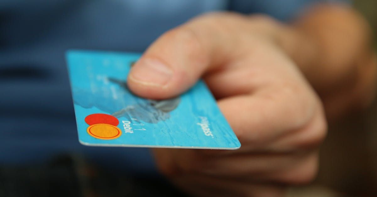 A person is holding a blue mastercard in their hand