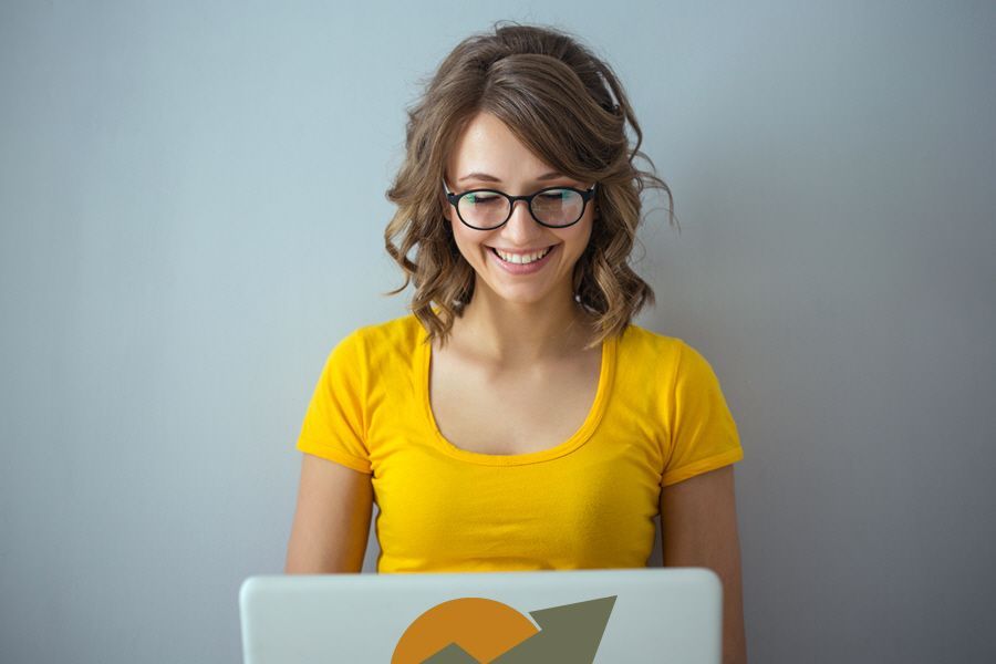 a woman wearing glasses is smiling while using a laptop computer