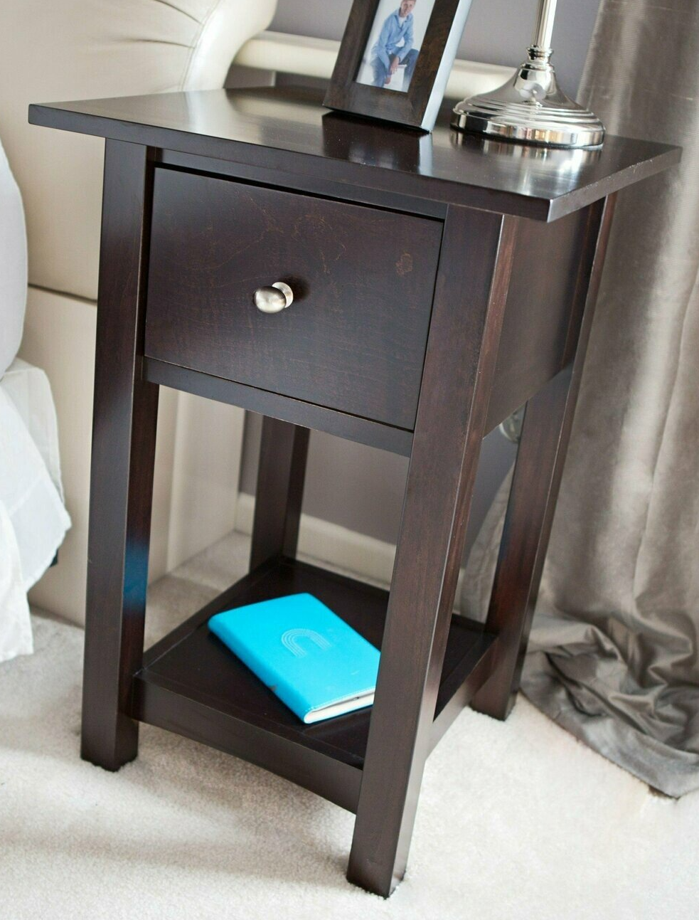 A nightstand with a blue book and a picture on top