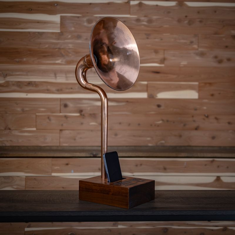A copper phonograph is sitting on a wooden table