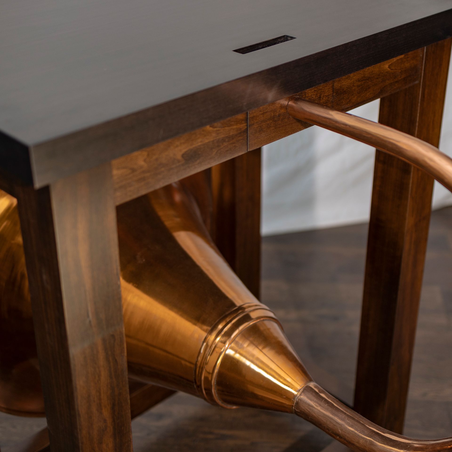 A wooden table with a copper watering can attached to it