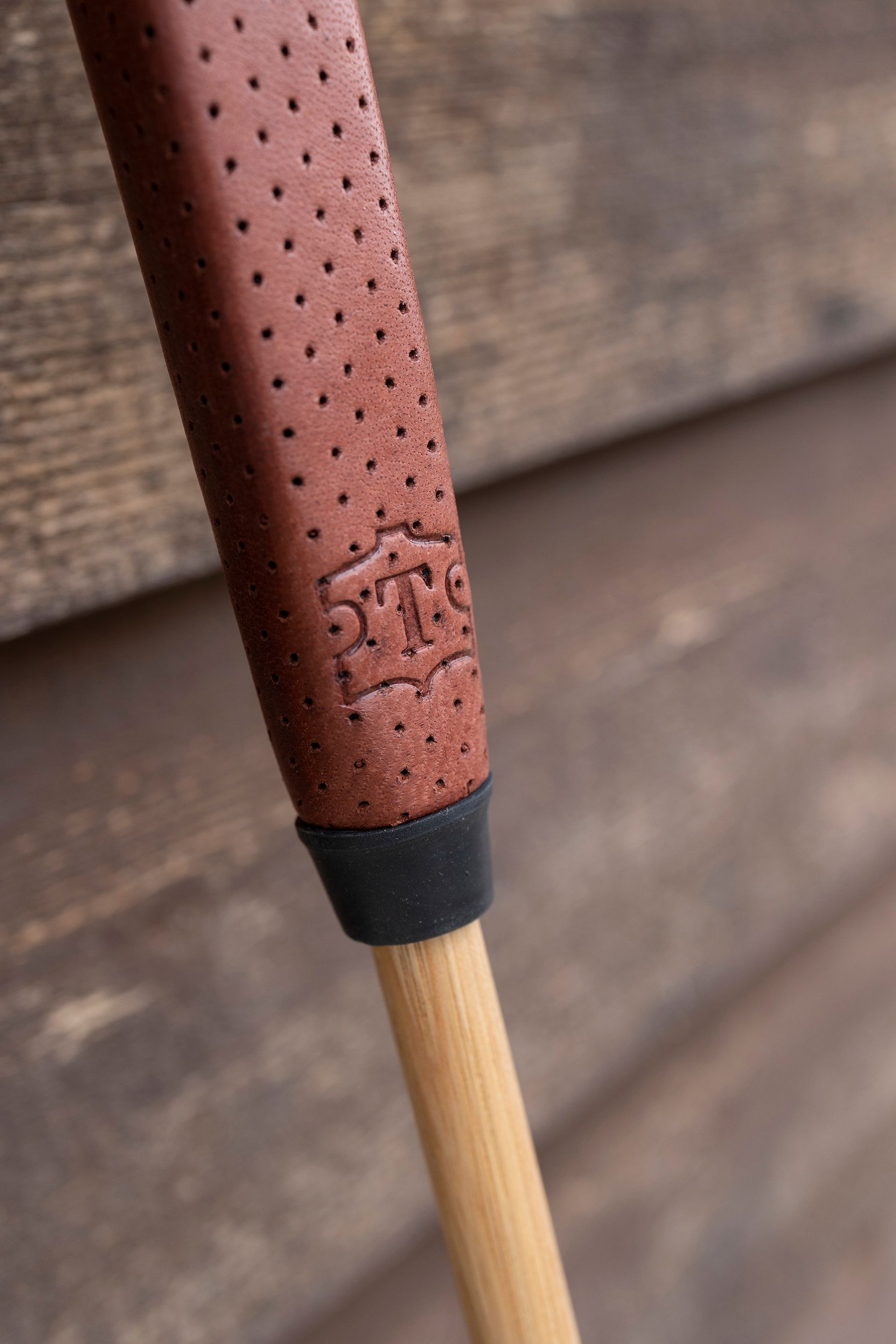 A close up of a golf club with a brown leather grip.