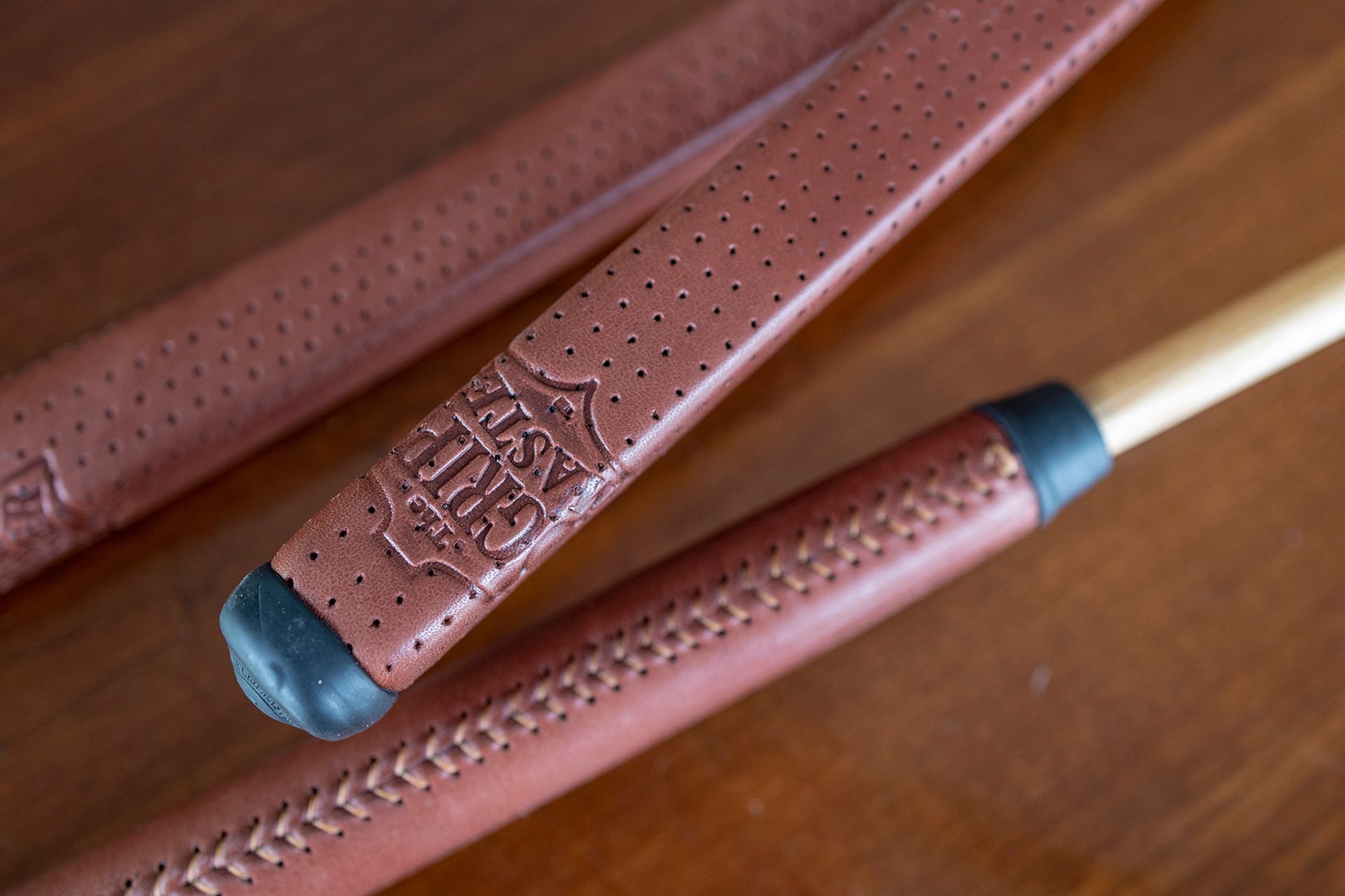 A pair of brown leather golf clubs are sitting on a wooden table.