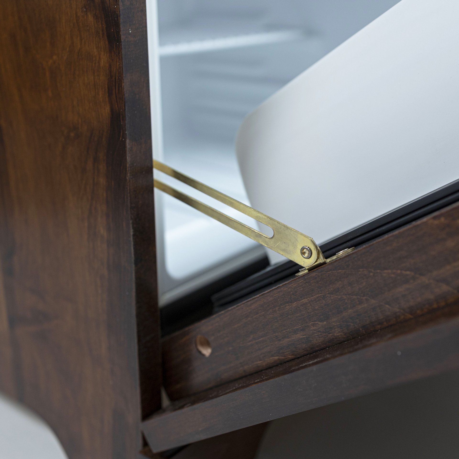 A close up of a wooden cabinet with a brass hinge