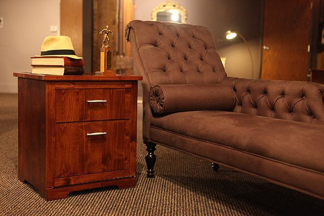 There is a chaise lounge and a nightstand in the room.