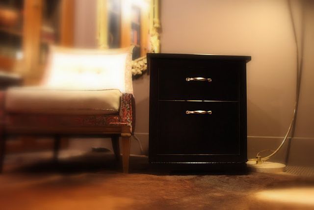 A black nightstand in a room next to a chair