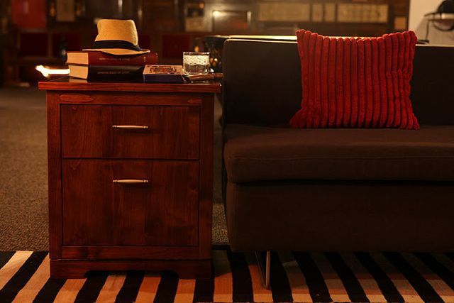 A red pillow sits on a nightstand next to a couch