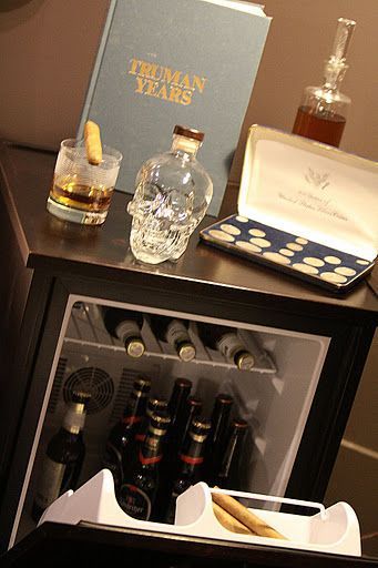 A small fridge filled with bottles of alcohol and a book on a table.