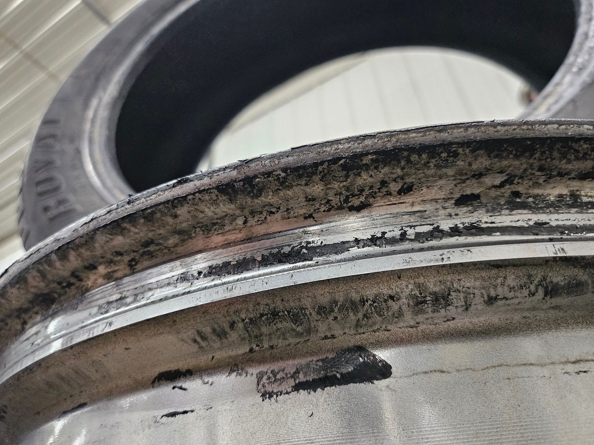 A close-up of a dirty, corroded car wheel rim with remnants of rubber tire debris along the edge. | Aurora Automotive
