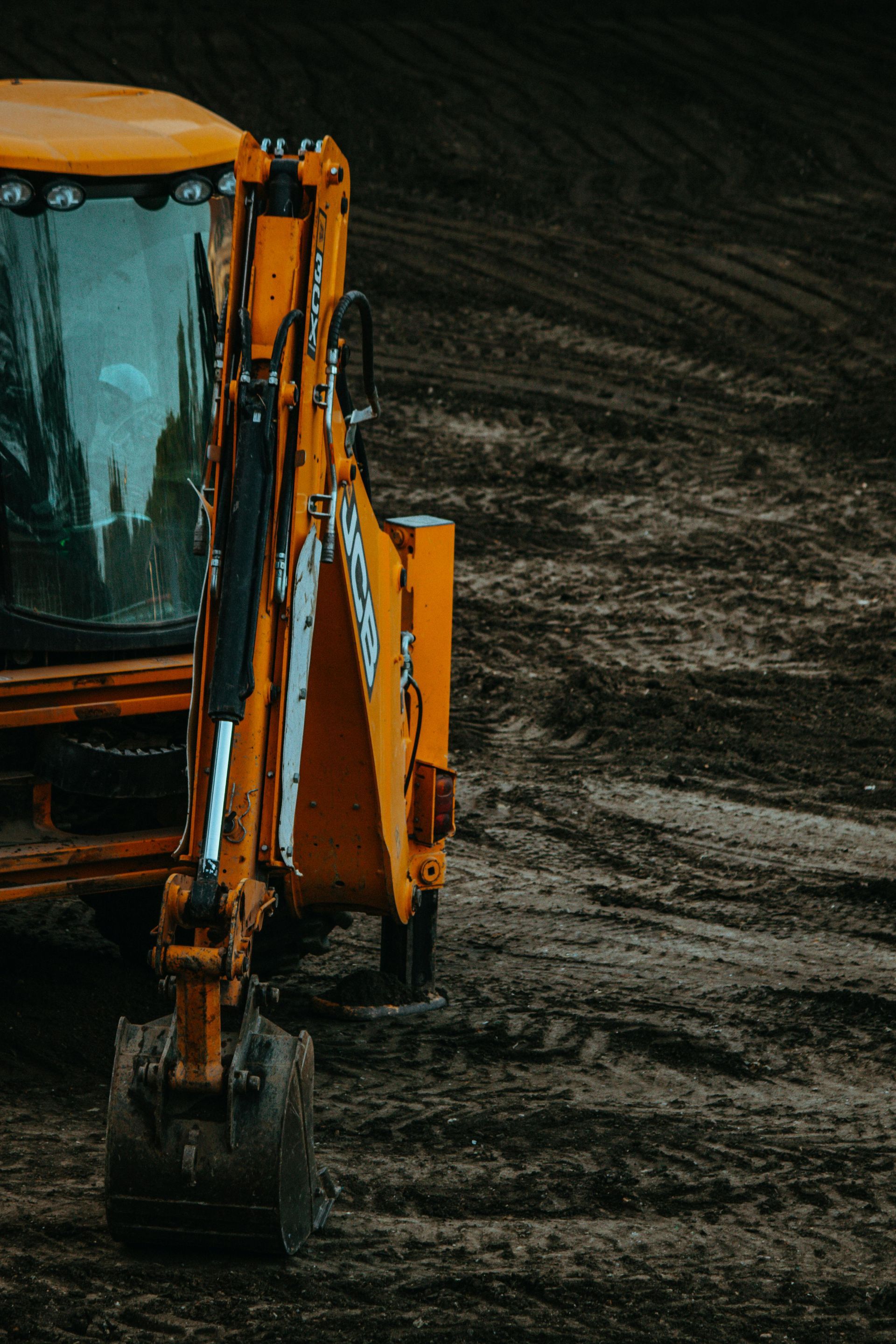Yellow backhoe on a muddy construction site, scooping earth.