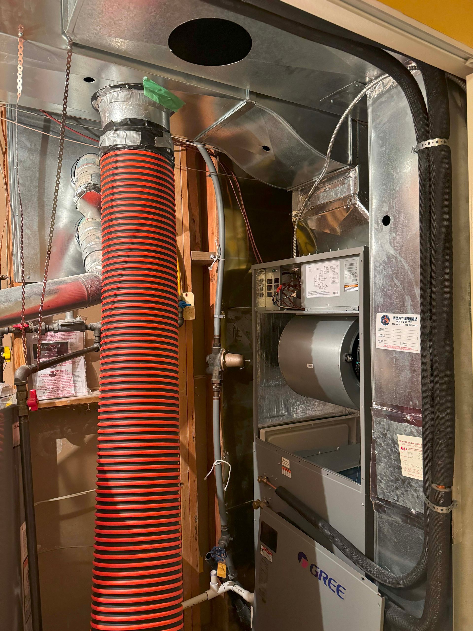 A red and black hose is coming out of a furnace.