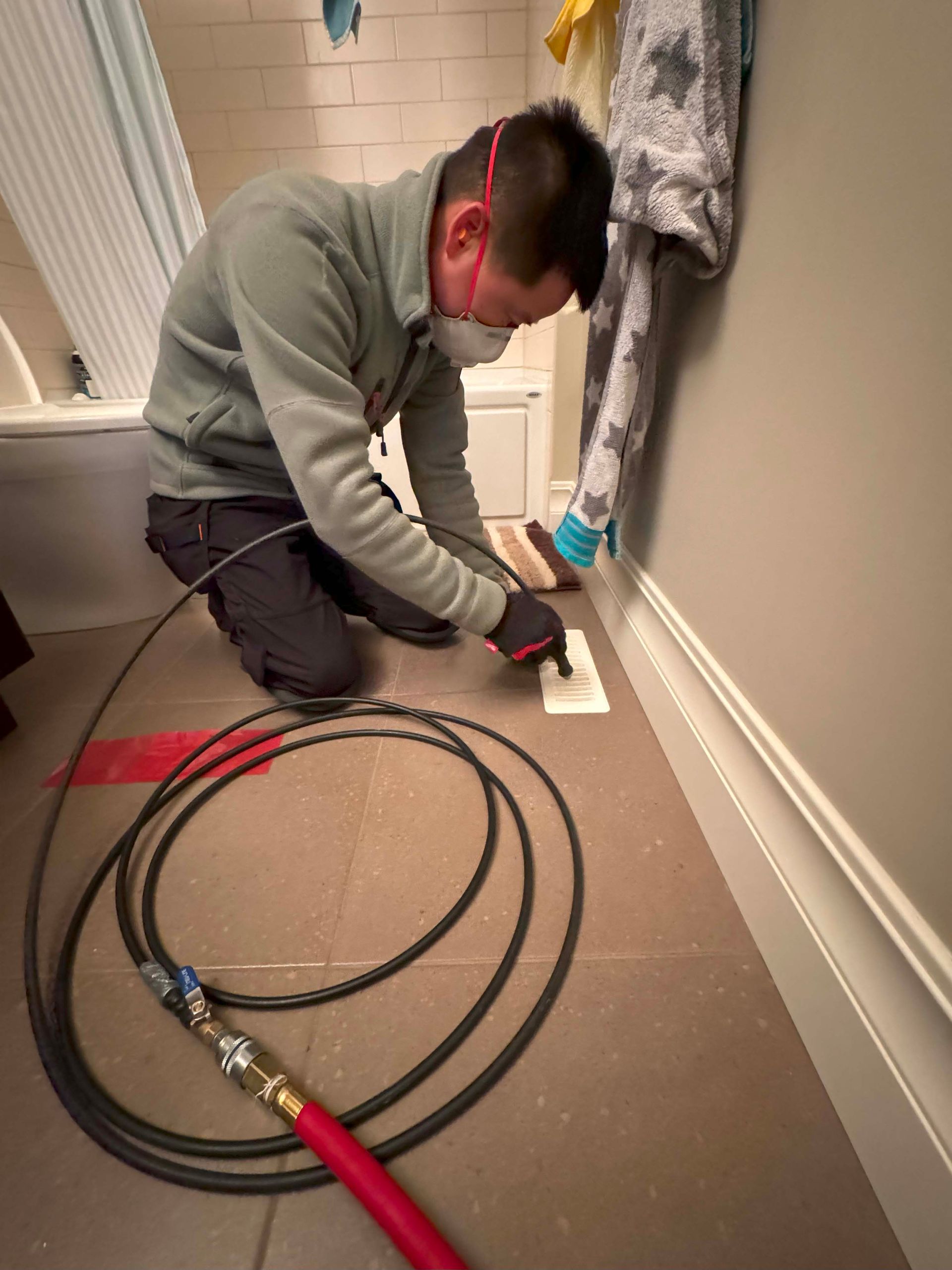 A man wearing a mask is working in a bathroom