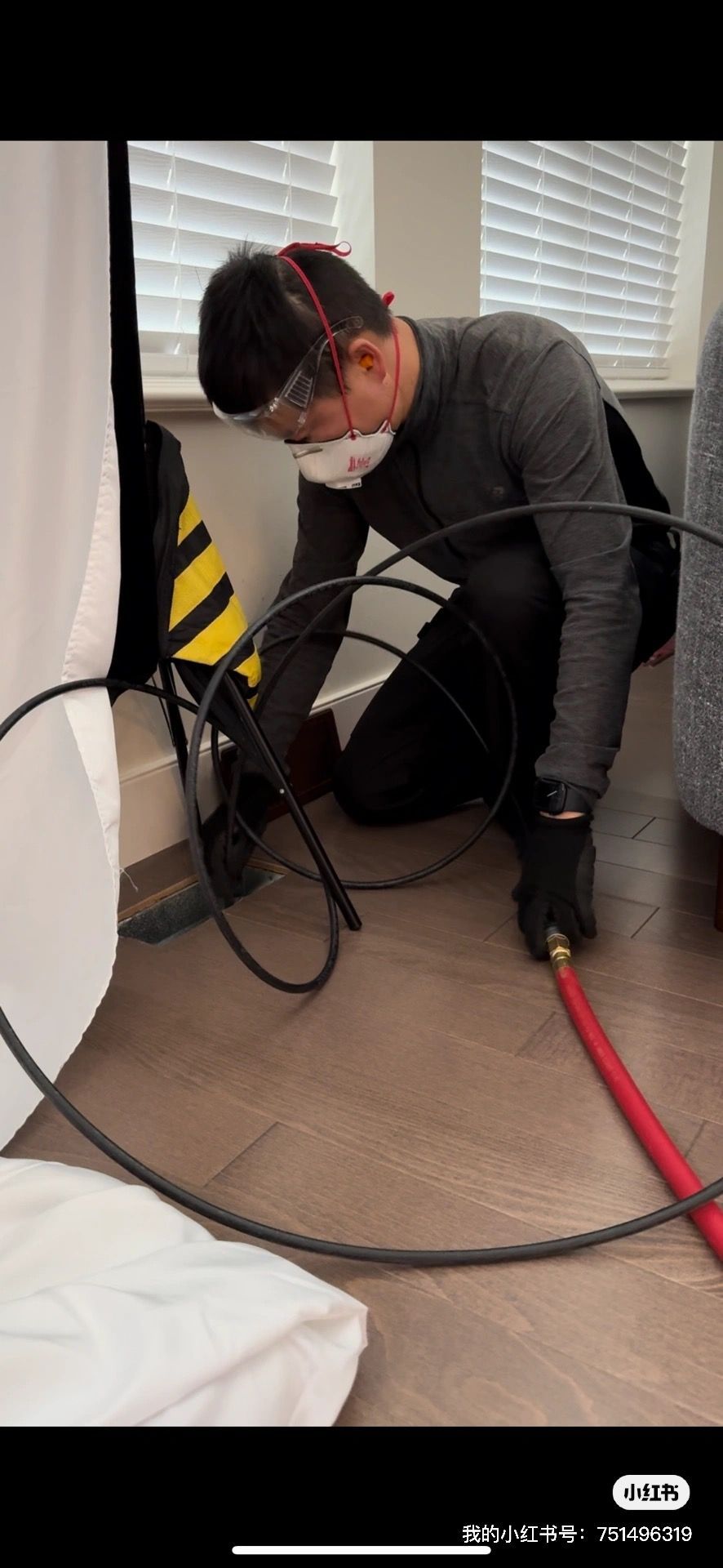 A man is kneeling down on the floor using a tool.