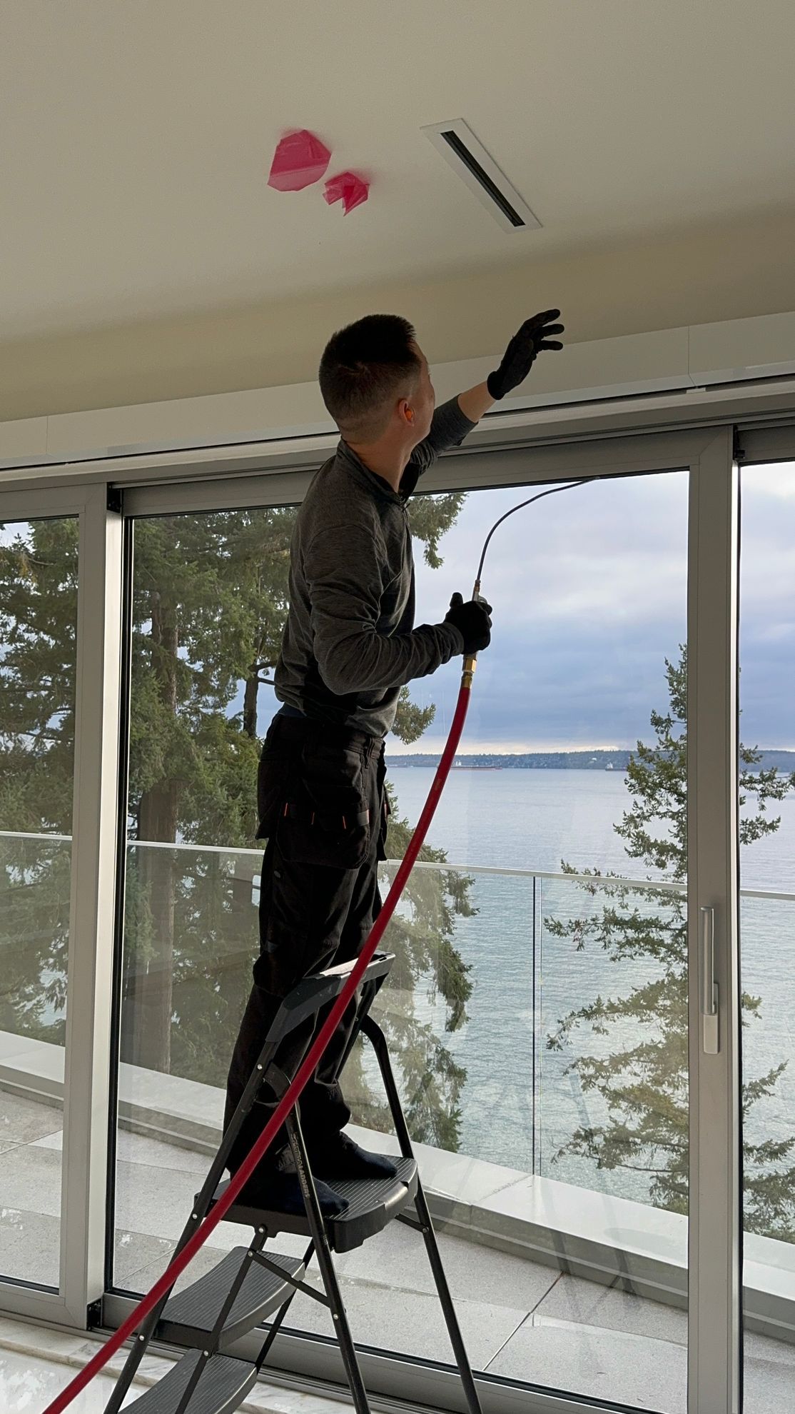 A man is standing on a ladder in front of a window.