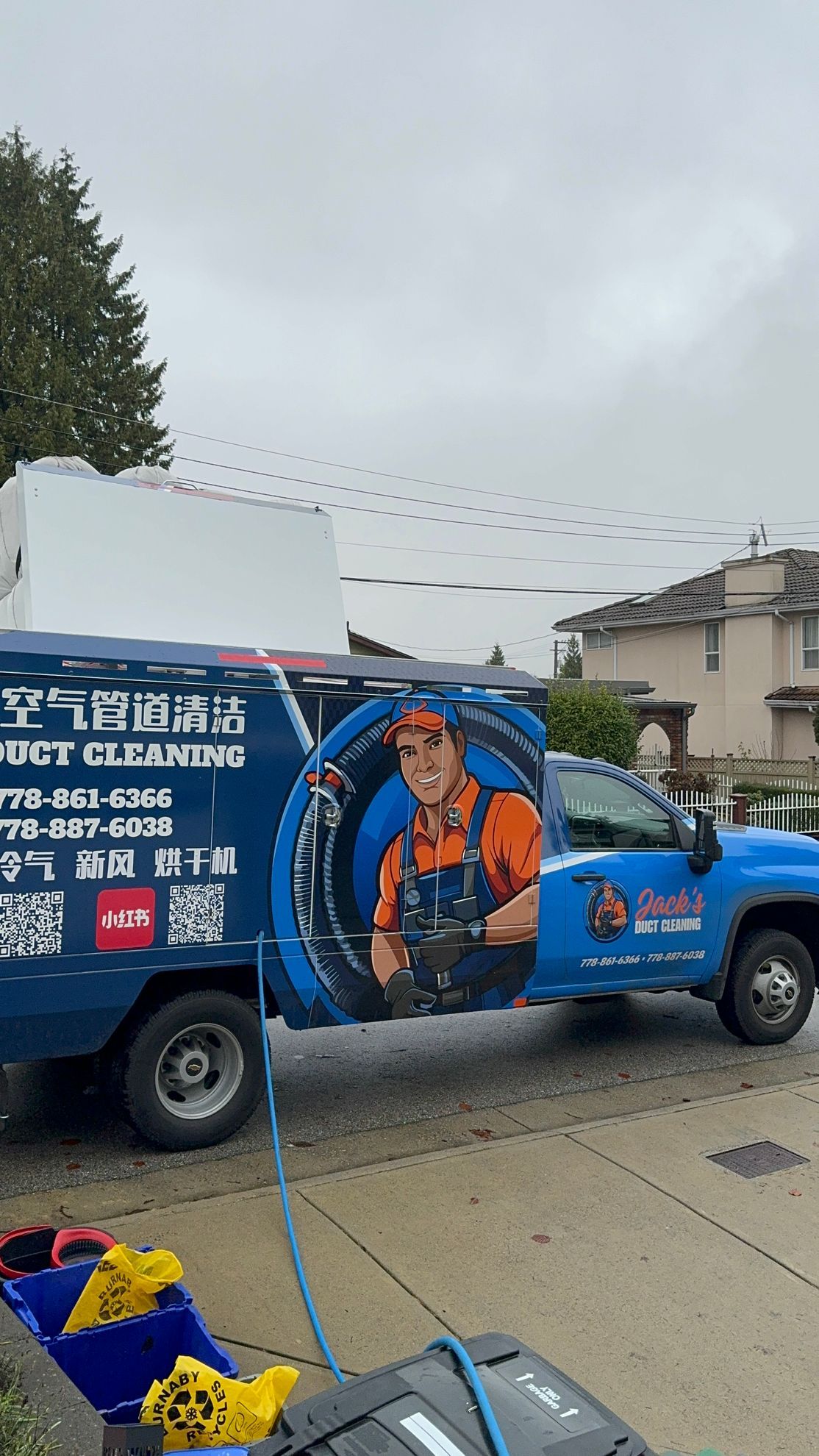 A blue truck with a plumber on the side is parked on the side of the road.