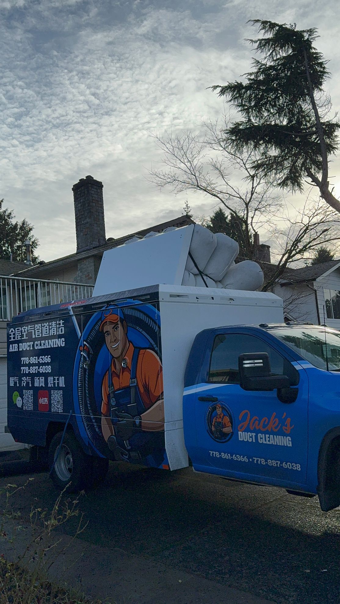 A blue and white truck with a plumber on the side is parked on the side of the road.